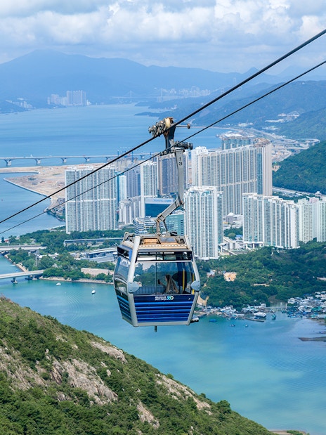 Cable car over Hong Kong landscape with city and water views.