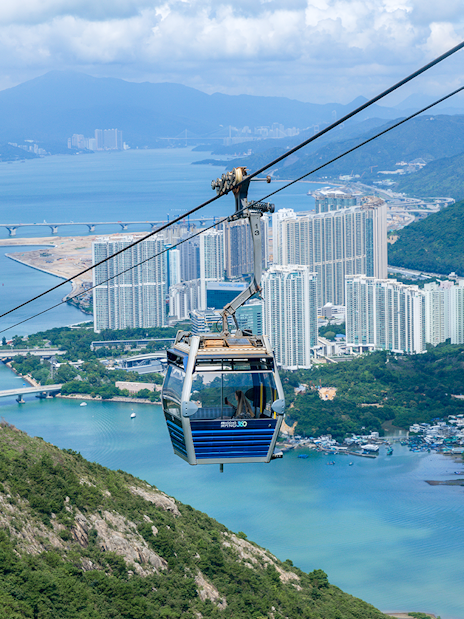 Cable car over Hong Kong landscape with city and water views.