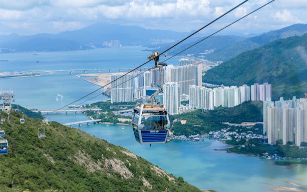 Cable car over Hong Kong landscape with city and water views.