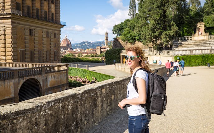 Visitor enjoying a sunny day at Boboli Gardens, Florence, with the Duomo in the background.