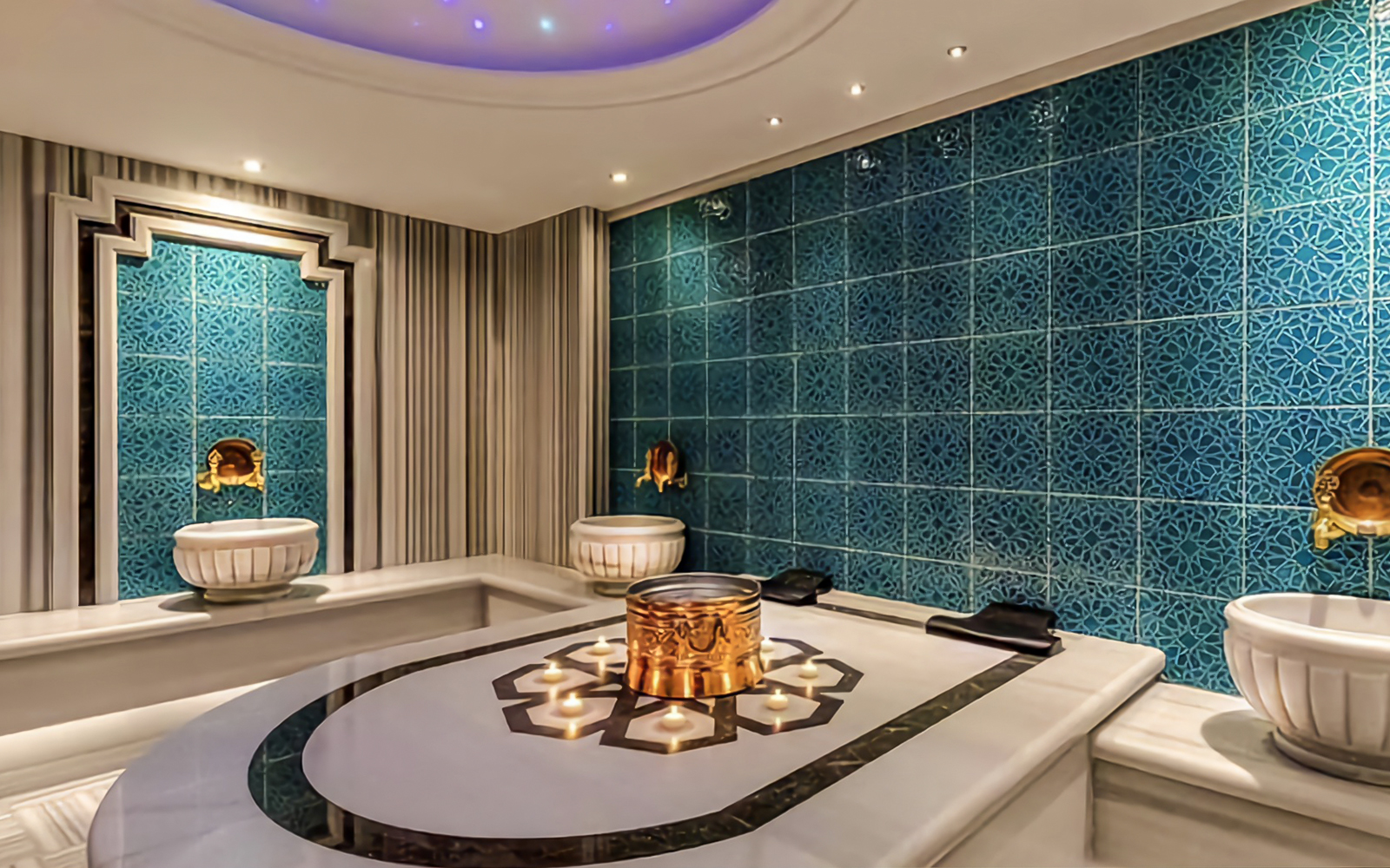 Private Turkish bath interior with ornate blue tiles and marble basins.
