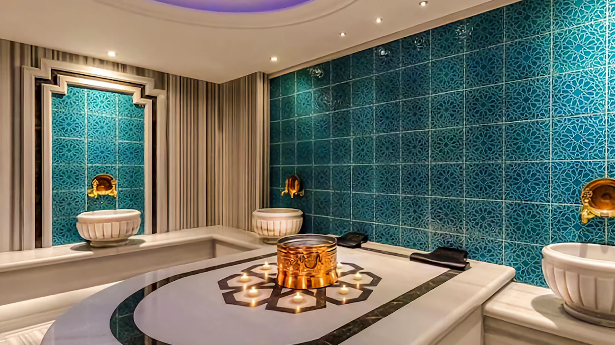 Private Turkish bath interior with ornate blue tiles and marble basins.
