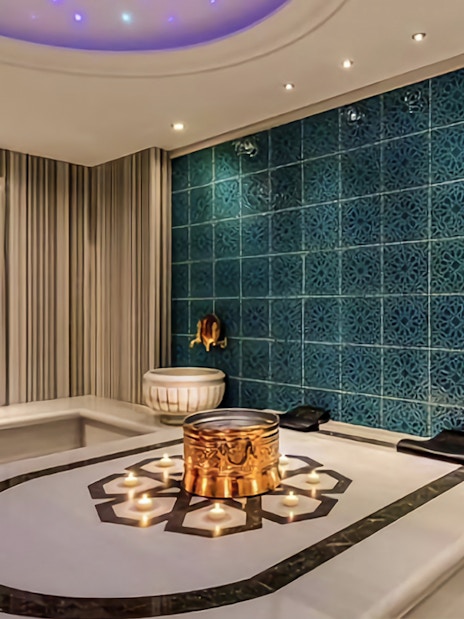 Private Turkish bath interior with ornate blue tiles and marble basins.