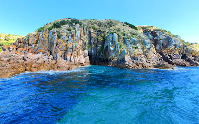 Cruise boat near rugged coastal cliffs at Cape Woolamai, Phillip Island.