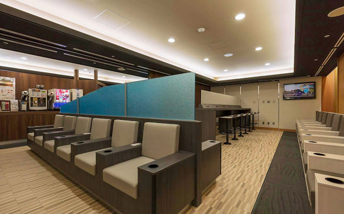 Waiting area seating at Narita International Airport Terminal 1 lounge with beverage station.
