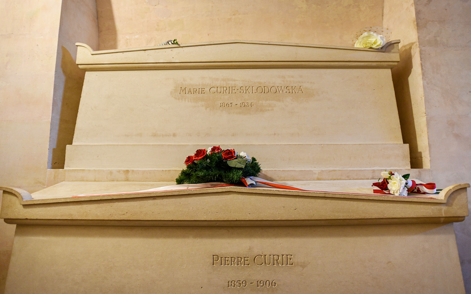 Marie Curie's tomb in Paris Pantheon with engraved name and surrounding marble structure.