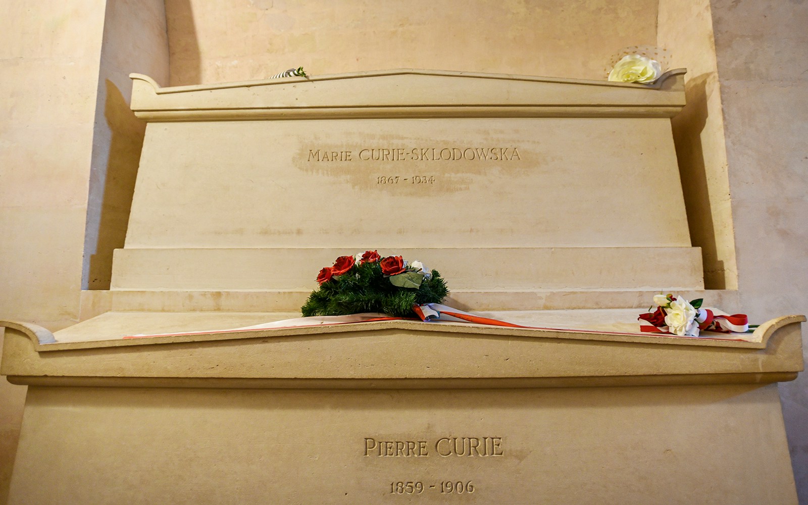 Marie Curie's tomb in Paris Pantheon with engraved name and surrounding marble structure.