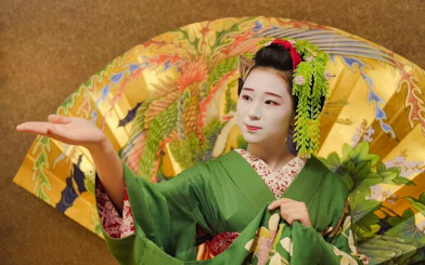 Geisha in traditional green kimono performing with ornate umbrella in Japan.
