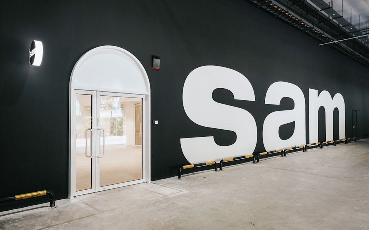 Entrance to Singapore Art Museum with large "Sam" sign on black wall.