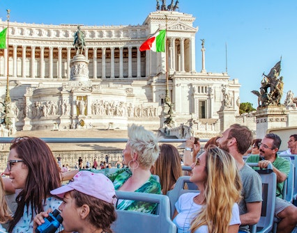 Tourists on a Rome hop-on hop-off bus viewing the Altare della Patria monument.