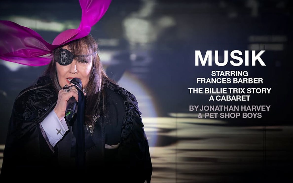 Performer with eyepatch and pink hat singing in "MUSIK" cabaret show.