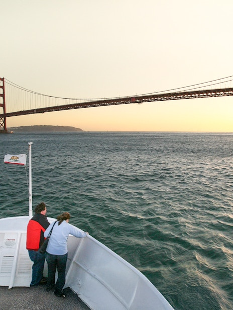 Guests on deck viewing Golden Gate Bridge during California sunset cruise.