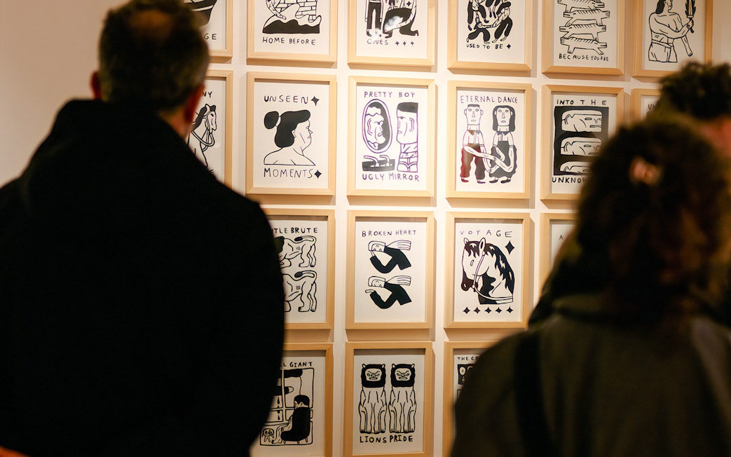 Visitors viewing framed artwork at Family & Legacy exhibition, Straat Museum.