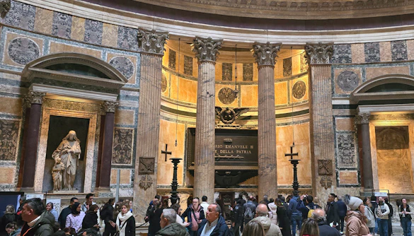 Interior view of Rome Pantheon with columns and visitors exploring the historic site.