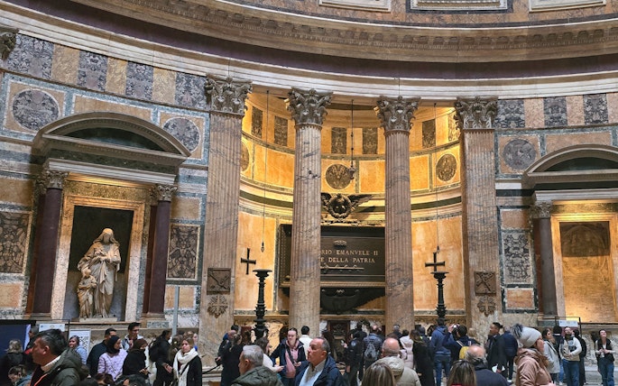 Interior view of Rome Pantheon with columns and visitors exploring the historic site.