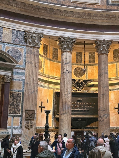 Interior view of Rome Pantheon with columns and visitors exploring the historic site.