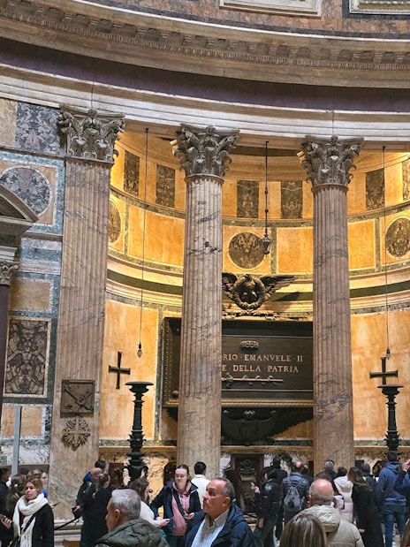 Interior view of Rome Pantheon with columns and visitors exploring the historic site.