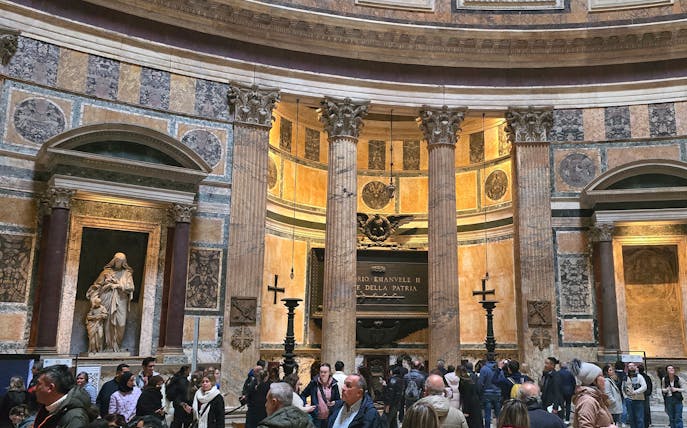 Interior view of Rome Pantheon with columns and visitors exploring the historic site.