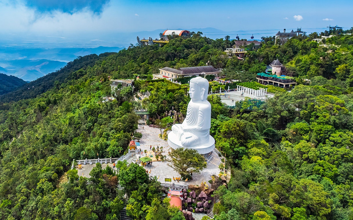 Ba Na Hills aerial view with large white Buddha statue surrounded by lush greenery.
