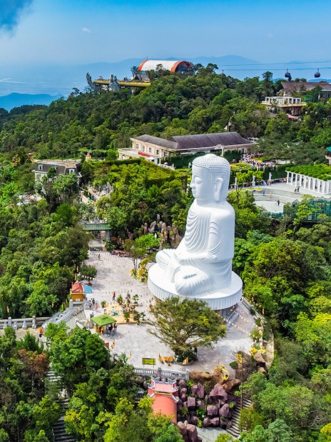 Ba Na Hills aerial view with large white Buddha statue surrounded by lush greenery.