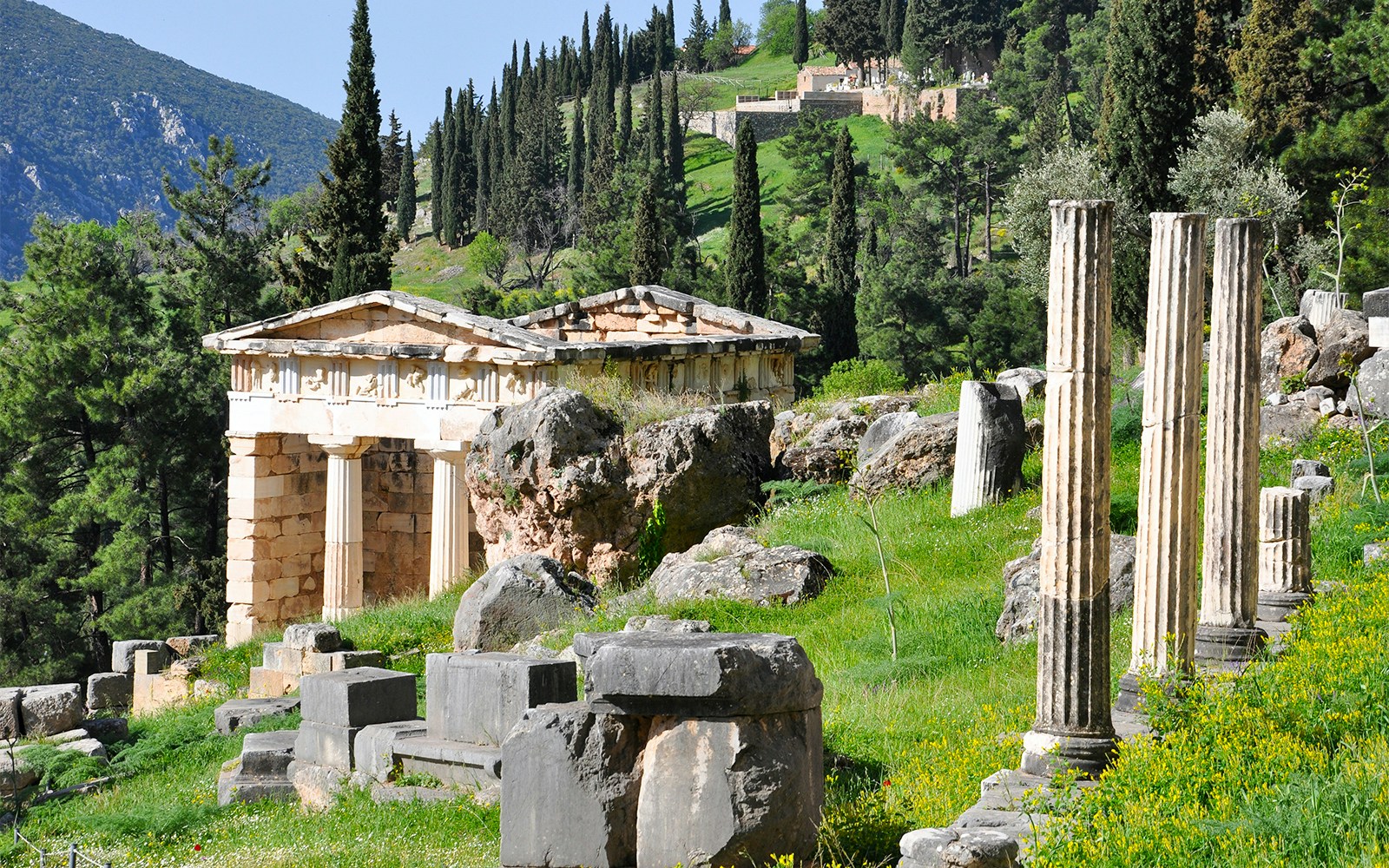 Temple of Apollo at Delphi with ancient columns and lush greenery in the background.