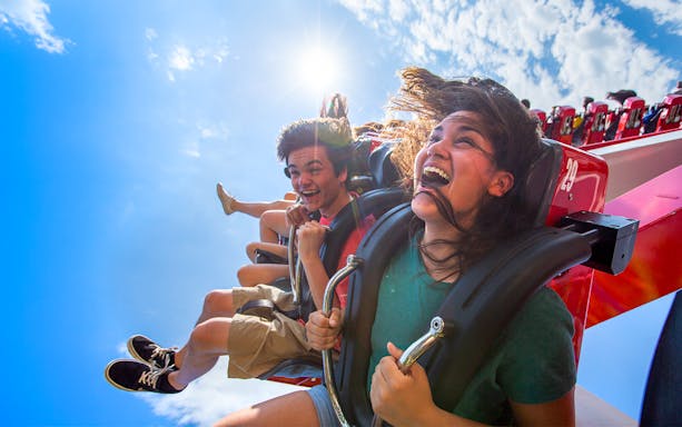 Riders enjoying HARLEY QUINN™ Spinsanity at Six Flags New England under a sunny sky.