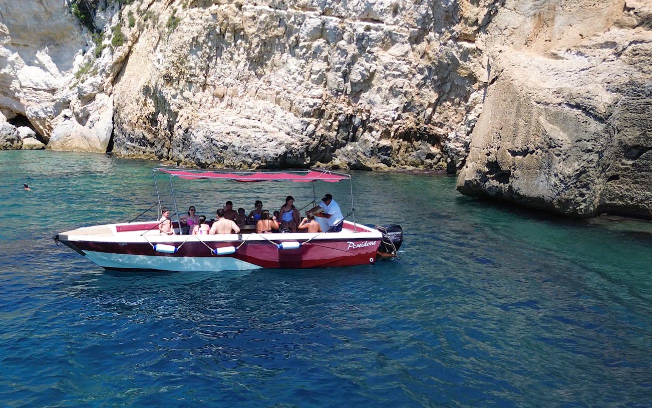 Boat tour at Ortigia Island Grotto with passengers near rocky cliffs.