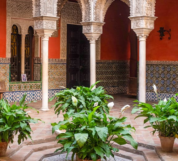 Courtyard with ornate arches and potted plants at Casa de Salinas, Seville.
