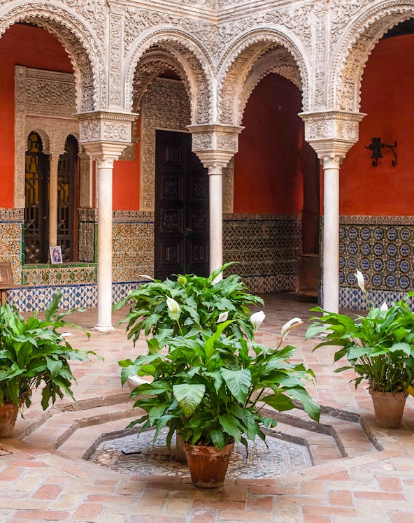 Courtyard with ornate arches and potted plants at Casa de Salinas, Seville.