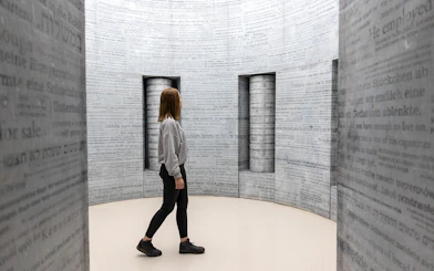 Woman exploring text-covered walls inside Oskar Schindler's Factory, Krakow.