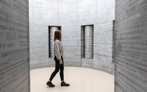 Woman exploring text-covered walls inside Oskar Schindler's Factory, Krakow.