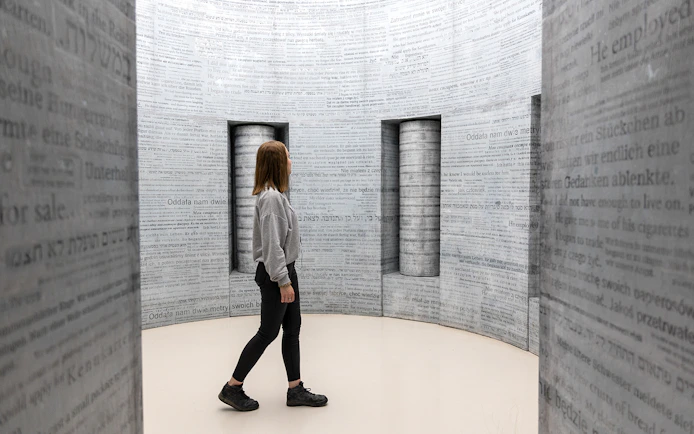 Woman exploring text-covered walls inside Oskar Schindler's Factory, Krakow.