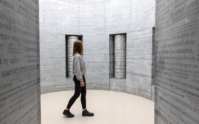 Woman exploring text-covered walls inside Oskar Schindler's Factory, Krakow.