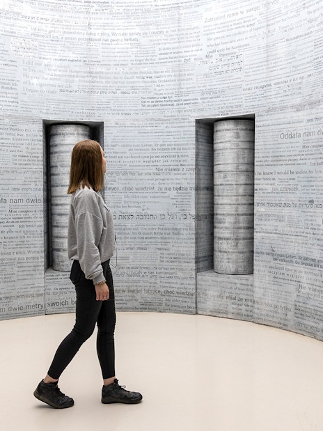 Woman exploring text-covered walls inside Oskar Schindler's Factory, Krakow.