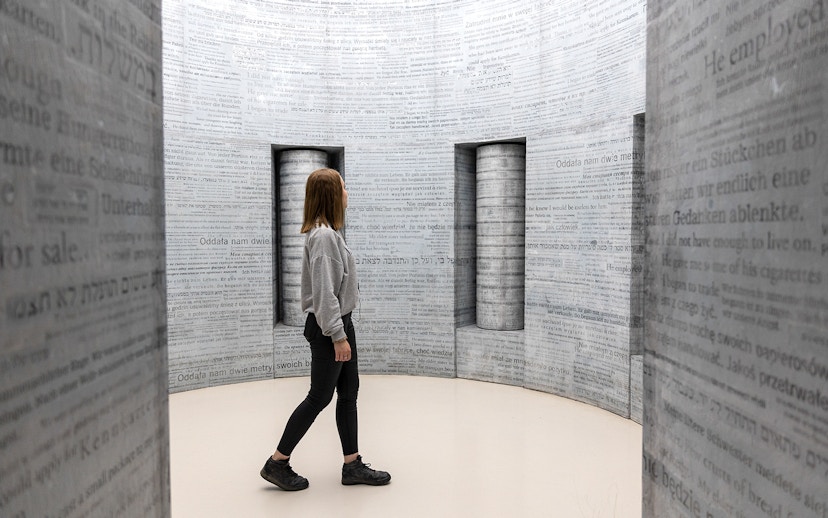 Woman exploring text-covered walls inside Oskar Schindler's Factory, Krakow.