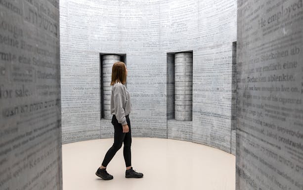 Woman exploring text-covered walls inside Oskar Schindler's Factory, Krakow.