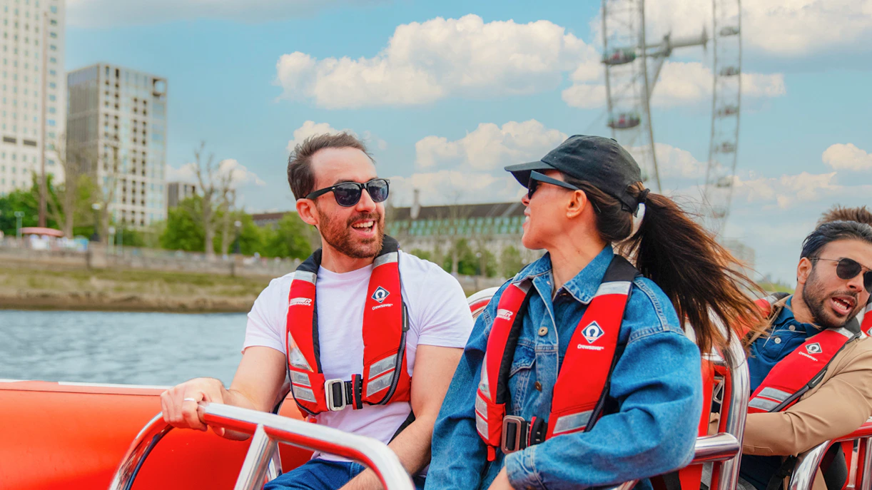 People enjoying a Thames speed boat ride with the London Eye in the background.
