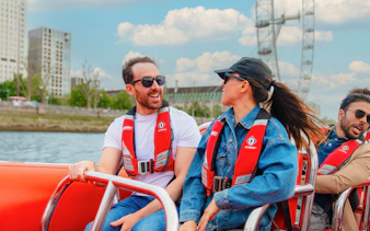 People enjoying a Thames speed boat ride with the London Eye in the background.
