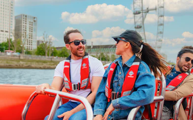 People enjoying a Thames speed boat ride with the London Eye in the background.