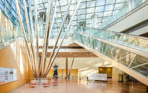 Sunlit lobby of The National Museum of Art, Osaka, with escalators to underground galleries.