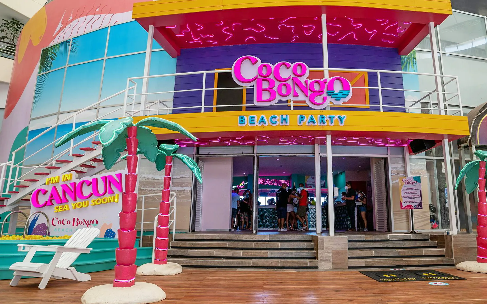 Coco Bongo Beach Party entrance in Cancun with colorful decor and palm tree sculptures.