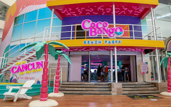 Coco Bongo Beach Party entrance in Cancun with colorful decor and palm tree sculptures.