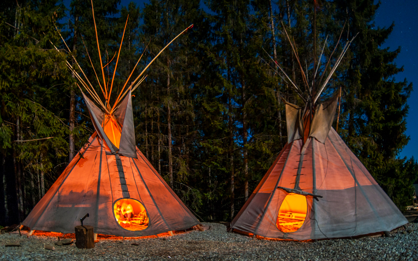 Teepees illuminated at night in the Tatra Mountains forest during Krakow dog sledding tour.