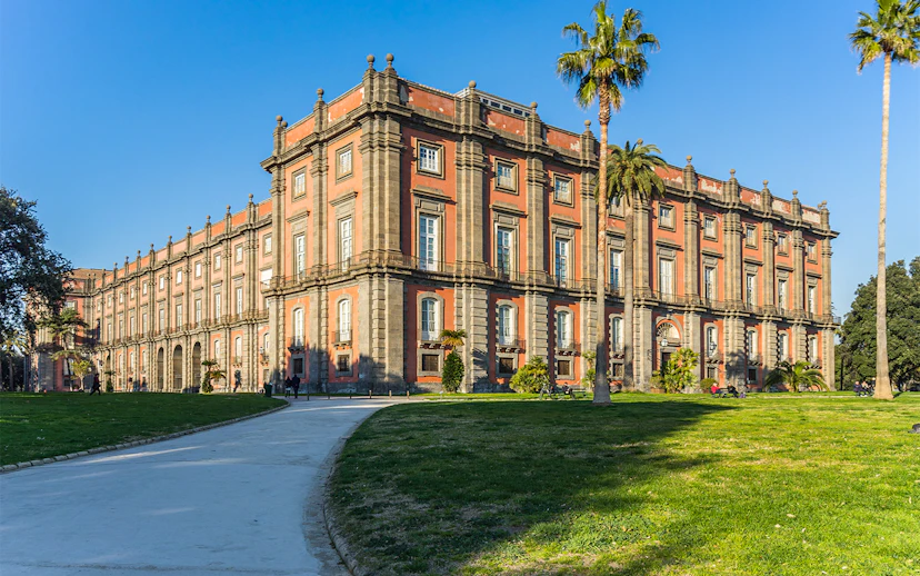 Capodimonte Museum exterior with palm trees and pathway in Naples, Italy.