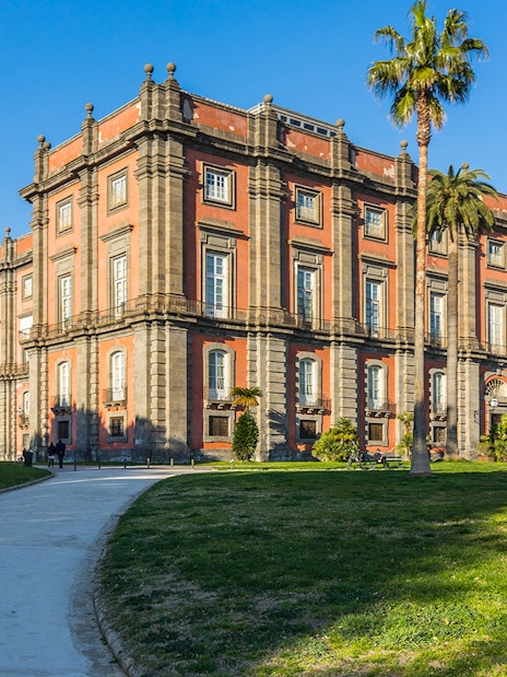 Capodimonte Museum exterior with palm trees and pathway in Naples, Italy.