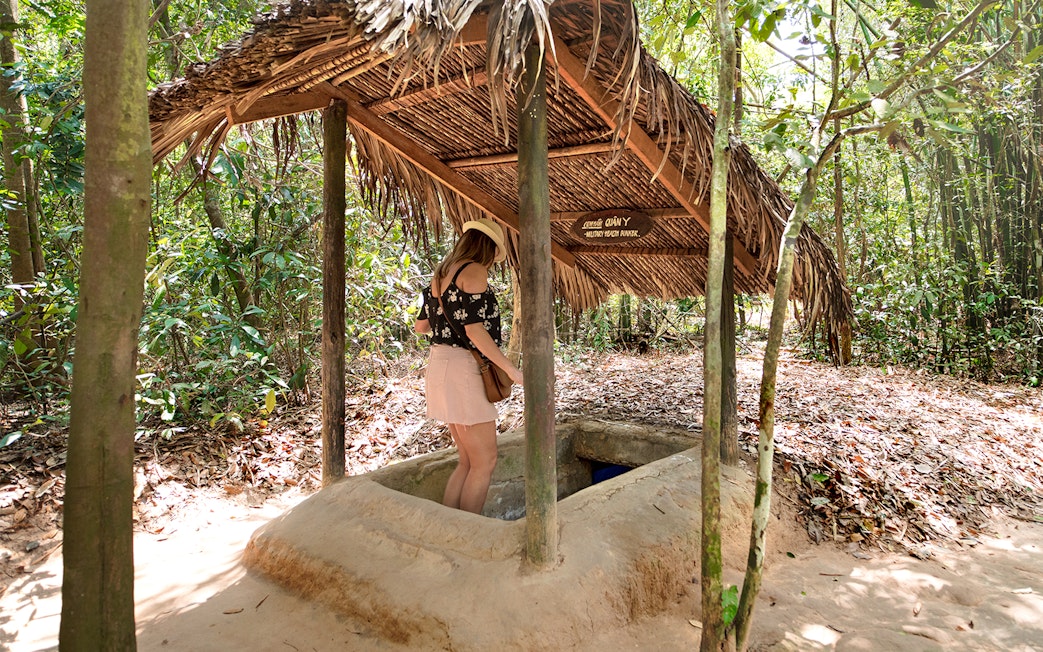 Girl descending into Cu Chi tunnels entrance in Vietnam.