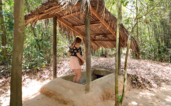 Girl descending into Cu Chi tunnels entrance in Vietnam.