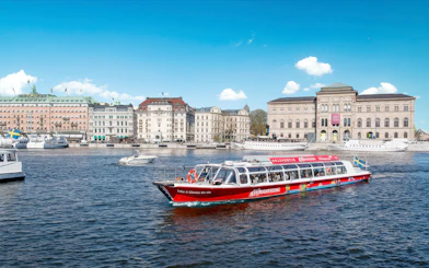Sightseeing boat on a canal in Stockholm, Sweden with historic buildings in the background.