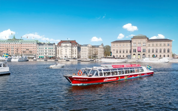 Sightseeing boat on a canal in Stockholm, Sweden with historic buildings in the background.