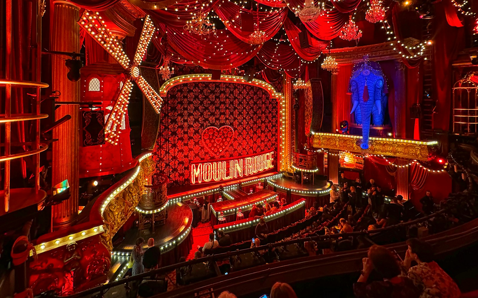 Moulin Rouge Paris interior with red velvet seating and ornate stage.